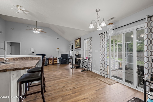 2902 Brems Battery, New Bern, NC 28562 - dining area with vaulted ceiling, a fireplace, light wood-type flooring, ceiling fan, and a chandelier