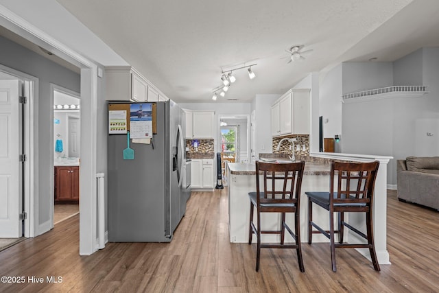 2902 Brems Battery, New Bern, NC 28562 - kitchen featuring stainless steel fridge with ice dispenser, light wood-style flooring, a peninsula, white cabinets, and a kitchen breakfast bar