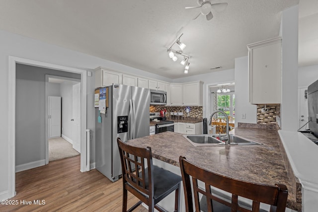 2902 Brems Battery, New Bern, NC 28562 - kitchen with appliances with stainless steel finishes, a peninsula, dark countertops, decorative backsplash, and light wood-style floors