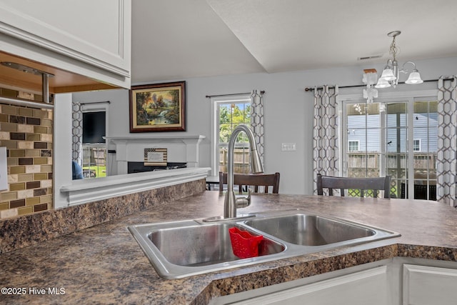 2902 Brems Battery, New Bern, NC 28562 - kitchen with a fireplace, a chandelier, dark countertops, white cabinetry, and decorative light fixtures