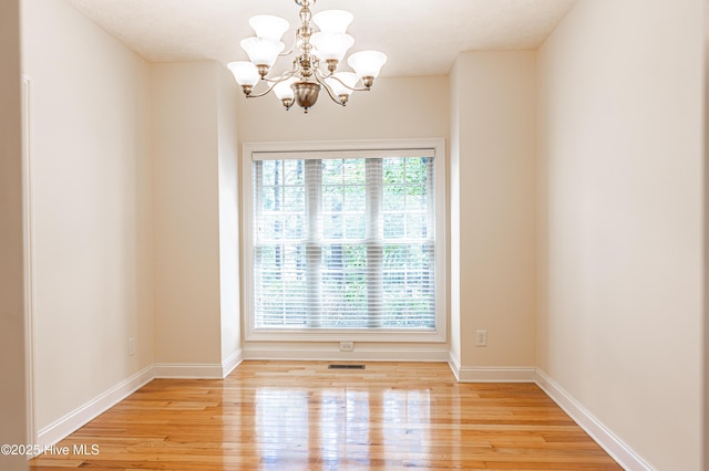 114 Baker Cir W, End, NC 27376 - spare room featuring a chandelier, light wood-style flooring, and baseboards