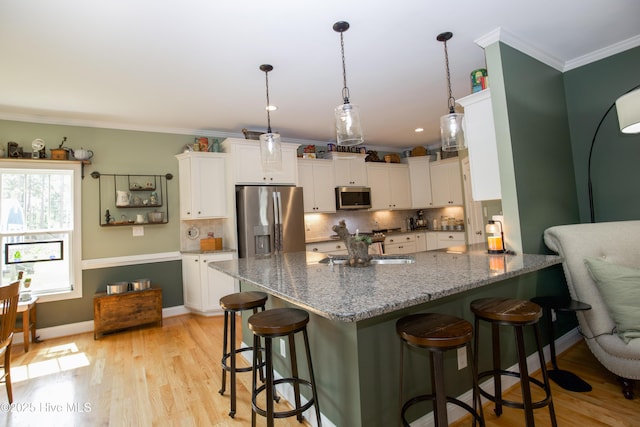 305 3rd St, Aberdeen, NC 28315 - kitchen featuring appliances with stainless steel finishes, white cabinets, a breakfast bar, a peninsula, and backsplash