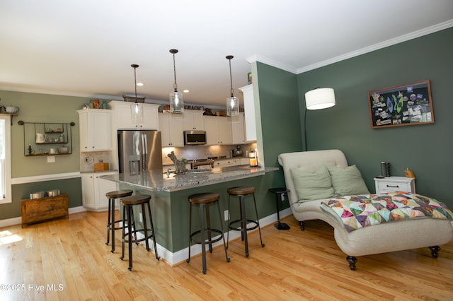 305 3rd St, Aberdeen, NC 28315 - kitchen featuring stainless steel appliances, a kitchen breakfast bar, white cabinetry, light wood-type flooring, and crown molding