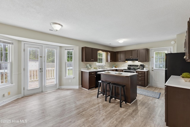1415 Setter Ct, Wilmington, NC 28411 - kitchen featuring black appliances, dark brown cabinetry, a textured ceiling, light countertops, and under cabinet range hood