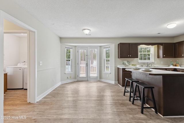 1415 Setter Ct, Wilmington, NC 28411 - kitchen with independent washer and dryer, dark brown cabinets, a breakfast bar area, light wood-style floors, and a textured ceiling