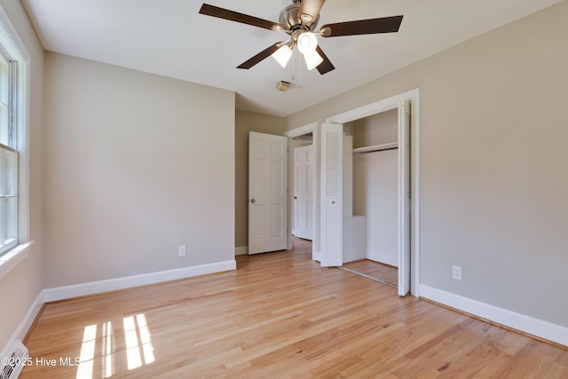 unfurnished bedroom featuring light wood-style floors, baseboards, multiple windows, and a closet