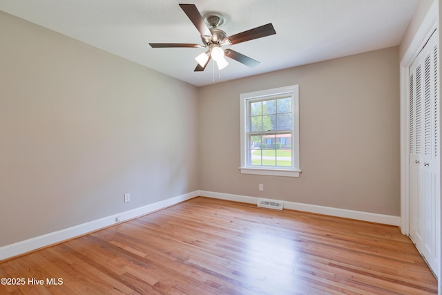unfurnished bedroom with a closet, light wood finished floors, baseboards, and a ceiling fan