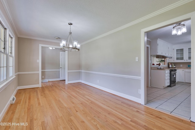 unfurnished dining area featuring a chandelier, light wood-style floors, ornamental molding, and baseboards
