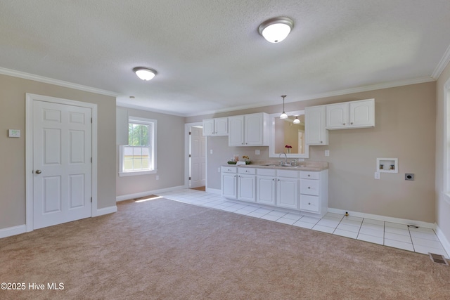 kitchen with a sink, crown molding, white cabinetry, baseboards, and light colored carpet