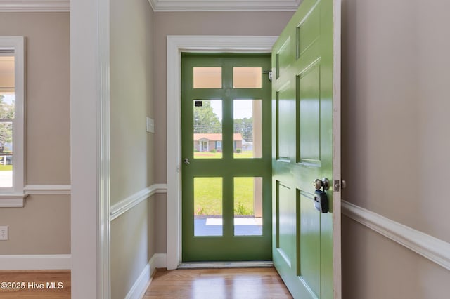 entryway with crown molding, wood finished floors, and baseboards