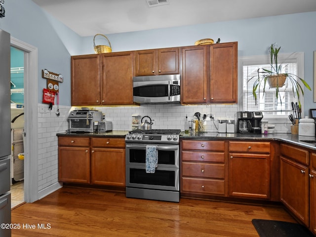 211 Brook Crossing Rd, Swansboro, NC 28584 - kitchen with stainless steel appliances, dark wood-type flooring, brown cabinetry, and a wainscoted wall