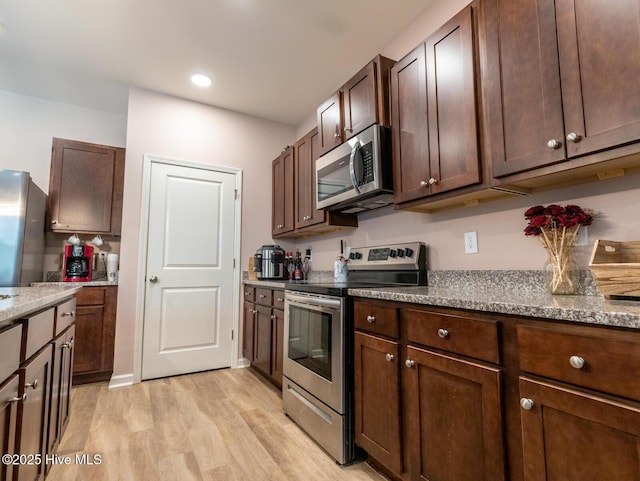 227 Cheswick Dr, Holly Ridge, NC 28445 - kitchen featuring appliances with stainless steel finishes, light wood-style flooring, light stone counters, dark brown cabinetry, and recessed lighting