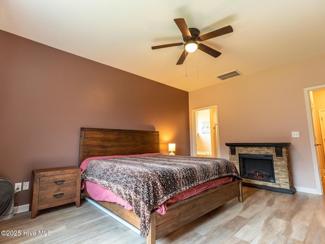 227 Cheswick Dr, Holly Ridge, NC 28445 - bedroom featuring wood finished floors, a stone fireplace, baseboards, and a ceiling fan