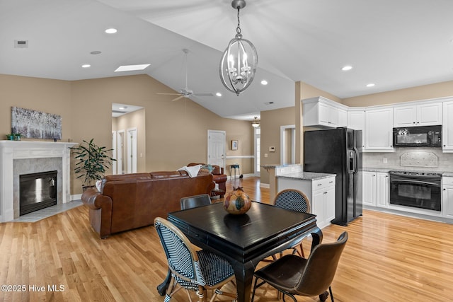 3101 Redfield Dr, Leland, NC 28451 - dining space with a fireplace with flush hearth, vaulted ceiling, a ceiling fan, light wood-style floors, and a chandelier