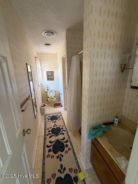 1164 Ocean Hwy N, Hertford, NC 27944 - full bath with wallpapered walls, a textured ceiling, a shower with shower curtain, vanity, and toilet