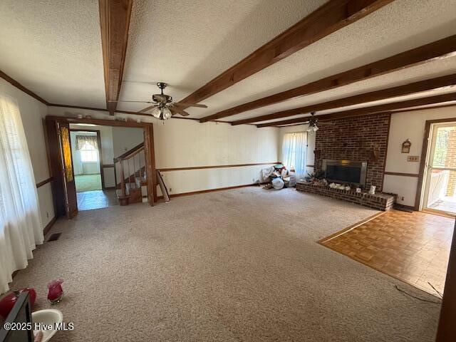 1164 Ocean Hwy N, Hertford, NC 27944 - unfurnished living room with plenty of natural light, a textured ceiling, a fireplace, a ceiling fan, and beamed ceiling