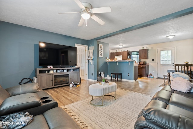 330 Brookfield Dr, Wilmington, NC 28405 - living room featuring light wood finished floors, ceiling fan, a textured ceiling, and a fireplace