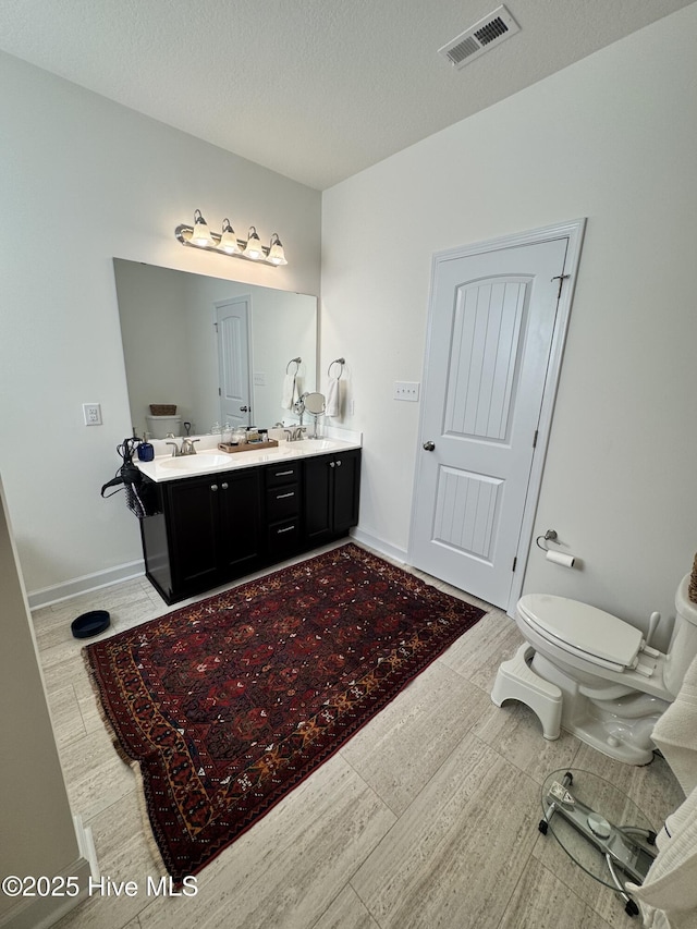 134 Longhorn Rd, Jacksonville, NC 28546 - bathroom featuring double vanity, toilet, baseboards, and a textured ceiling