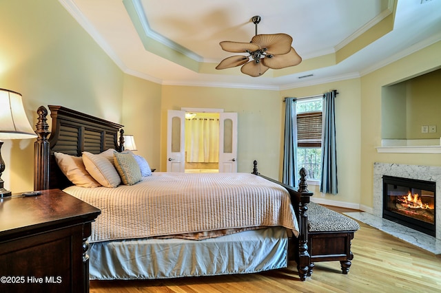 1711 Heather Run Ct SE, Bolivia, NC 28422 - bedroom featuring a tray ceiling, crown molding, wood finished floors, a fireplace, and a ceiling fan