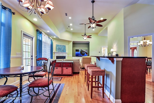 1711 Heather Run Ct SE, Bolivia, NC 28422 - dining space featuring a chandelier, light wood-style flooring, a fireplace, vaulted ceiling, and recessed lighting