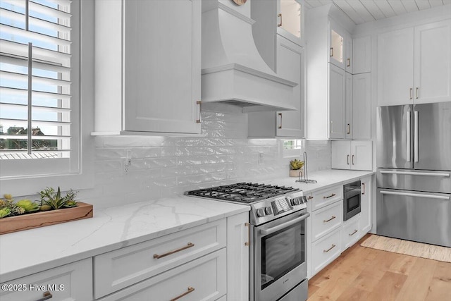 209 S 11th St, Morehead City, NC 28557 - kitchen with stainless steel appliances, custom range hood, white cabinetry, and tasteful backsplash