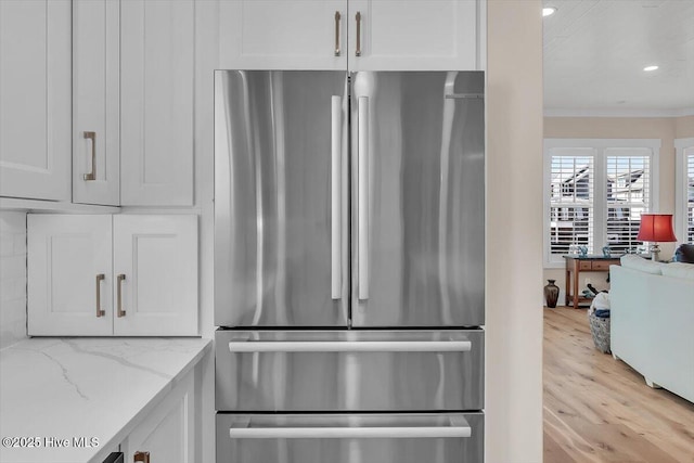 209 S 11th St, Morehead City, NC 28557 - kitchen view of freestanding refrigerator, white cabinetry, ornamental molding, light wood-style flooring, and light stone countertops