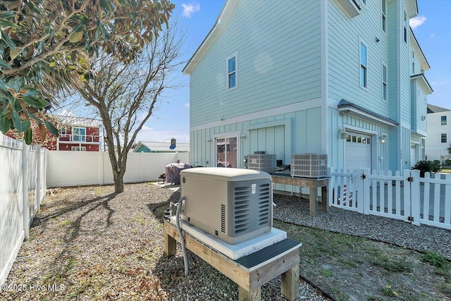 209 S 11th St, Morehead City, NC 28557 - rear view of house with board and batten siding, an attached garage, central AC unit, and a fenced backyard