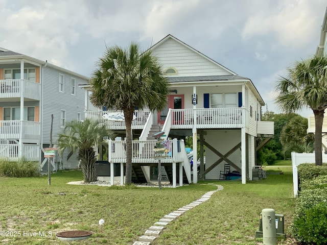 108 W Dolphin Dr, Oak Island, NC 28465 - back of house with stairway, a lawn, and covered porch