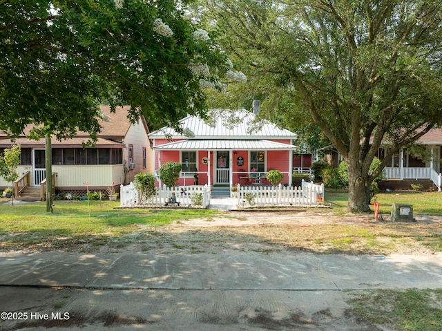 209 W St George St, Southport, NC 28461 - view of front facade featuring a porch, a fenced front yard, a sunroom, and metal roof