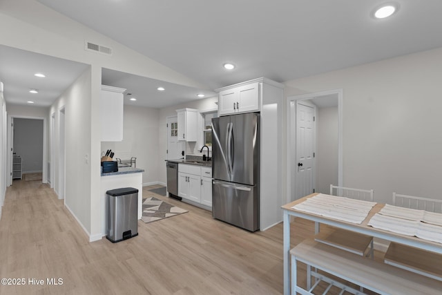 5302 Autumn Dr, Wilmington, NC 28409 - kitchen featuring stainless steel appliances, light wood-type flooring, white cabinets, vaulted ceiling, and recessed lighting