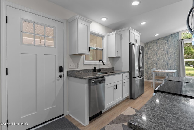 5302 Autumn Dr, Wilmington, NC 28409 - kitchen with appliances with stainless steel finishes, a sink, white cabinets, dark stone counters, and light wood-style floors