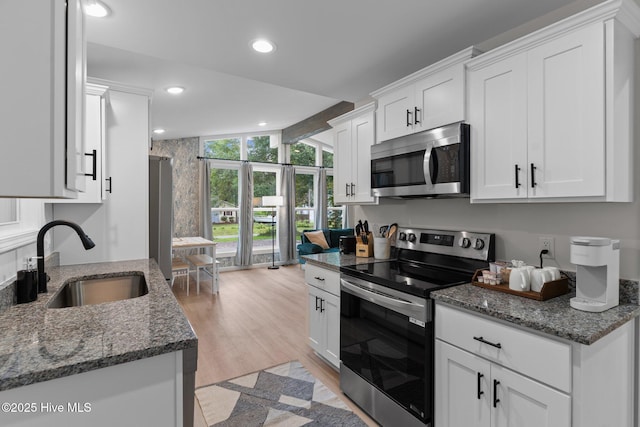 5302 Autumn Dr, Wilmington, NC 28409 - kitchen featuring appliances with stainless steel finishes, a sink, white cabinets, light wood-type flooring, and recessed lighting