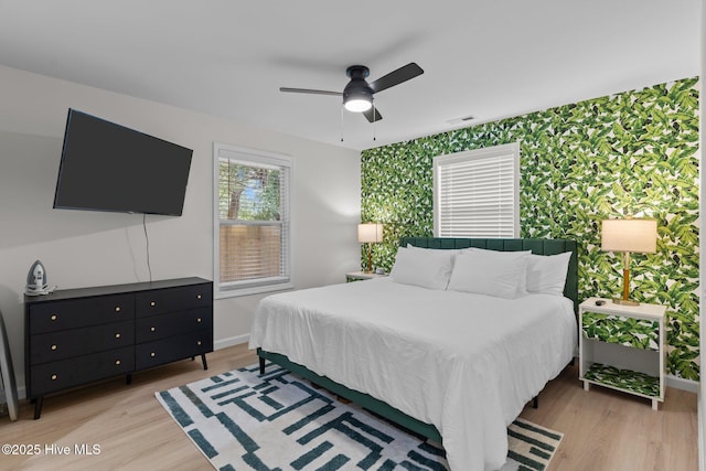 5302 Autumn Dr, Wilmington, NC 28409 - bedroom featuring wallpapered walls, an accent wall, baseboards, light wood-style floors, and ceiling fan