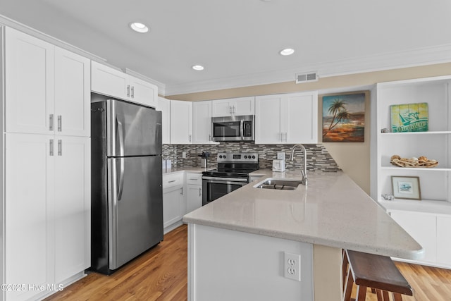 612 N Carolina Beach Ave Unit 3A, Carolina Beach, NC 28428 - kitchen with appliances with stainless steel finishes, a peninsula, a sink, a breakfast bar, and white cabinets