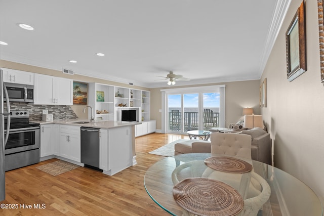 612 N Carolina Beach Ave Unit 3A, Carolina Beach, NC 28428 - kitchen with appliances with stainless steel finishes, open floor plan, a peninsula, ornamental molding, and white cabinets