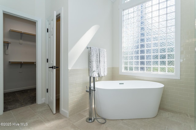 24 Mcnish Rd, Southern Pines, NC 28387 - full bathroom featuring a freestanding tub, a walk in closet, tile walls, tile patterned floors, and wainscoting