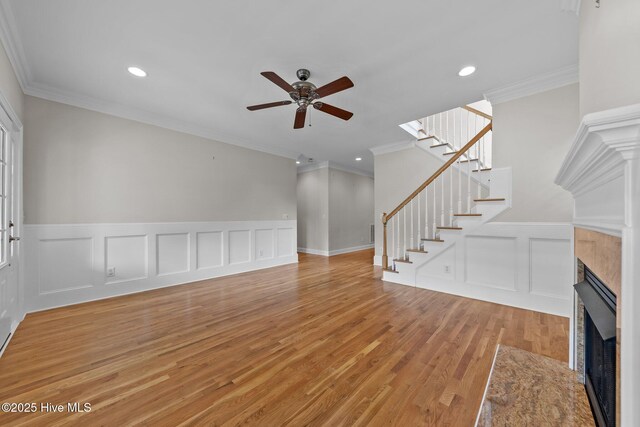 30 Deacon Palmer Pl, Southern Pines, NC 28387 - unfurnished living room with a decorative wall, ornamental molding, ceiling fan, a tiled fireplace, and light wood-style flooring