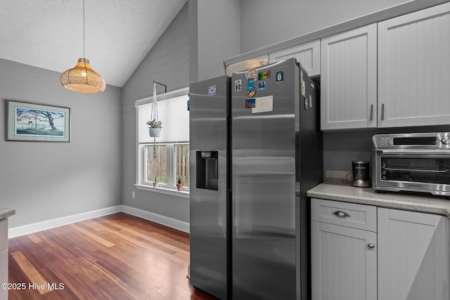 8122 Bahia Honda Dr, Wilmington, NC 28412 - kitchen with stainless steel fridge with ice dispenser, vaulted ceiling, wood finished floors, baseboards, and hanging light fixtures