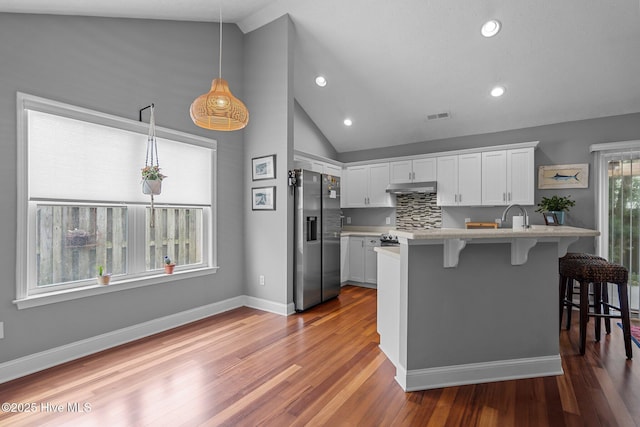 8122 Bahia Honda Dr, Wilmington, NC 28412 - kitchen featuring stainless steel refrigerator with ice dispenser, under cabinet range hood, a kitchen breakfast bar, a peninsula, and white cabinets