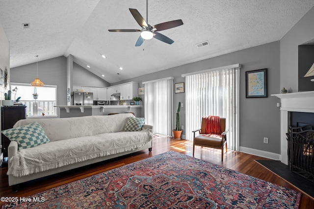 8122 Bahia Honda Dr, Wilmington, NC 28412 - living room featuring wood finished floors, a ceiling fan, vaulted ceiling, a fireplace with flush hearth, and a textured ceiling
