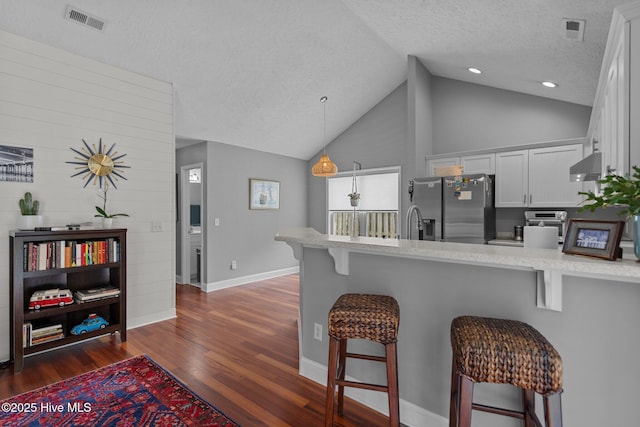 8122 Bahia Honda Dr, Wilmington, NC 28412 - kitchen with stainless steel refrigerator with ice dispenser, a textured ceiling, a peninsula, under cabinet range hood, and vaulted ceiling