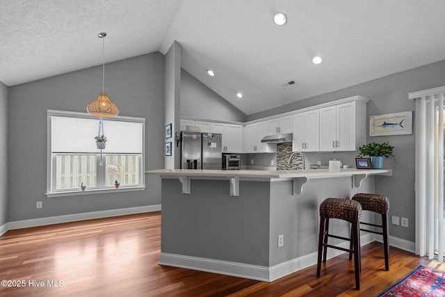 8122 Bahia Honda Dr, Wilmington, NC 28412 - kitchen featuring stainless steel fridge, under cabinet range hood, lofted ceiling, a peninsula, and a breakfast bar area