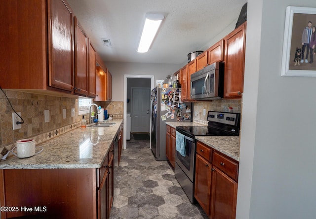 306 Top Knot Rd, Hubert, NC 28539 - kitchen with appliances with stainless steel finishes, backsplash, light stone counters, a sink, and brown cabinets