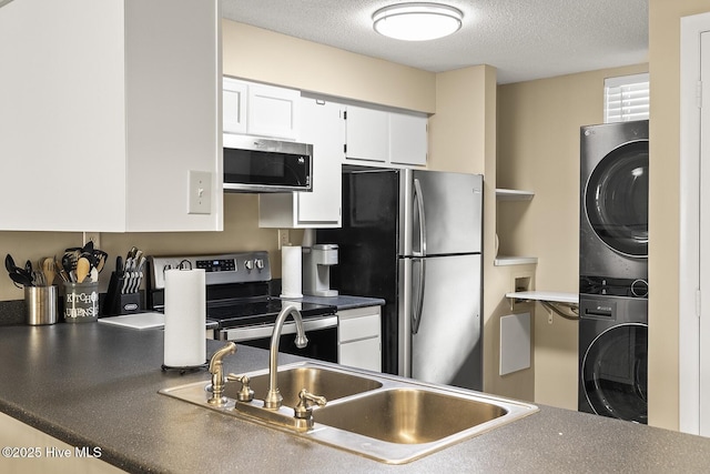 1505 Salter Path Rd Unit 328, Indian Beach, NC 28512 - kitchen featuring stainless steel appliances, stacked washing machine and dryer, a sink, a textured ceiling, and white cabinets