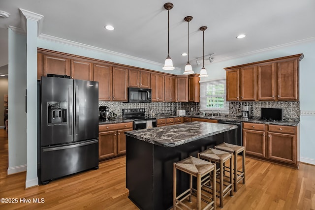 4301 Gainesford Ct, Wilmington, NC 28412 - kitchen with black appliances, crown molding, light wood-style floors, a kitchen breakfast bar, and backsplash