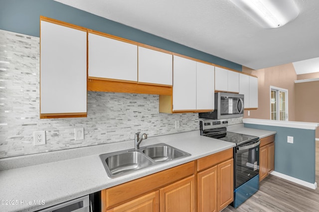 711 Navaho Trl, Wilmington, NC 28409 - kitchen with stainless steel appliances, light countertops, decorative backsplash, light wood-style flooring, and white cabinets