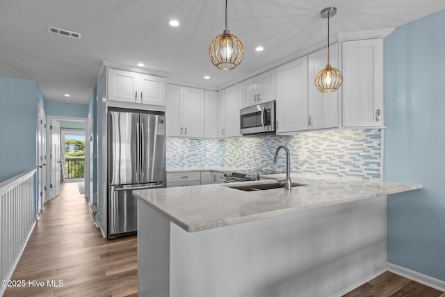 535 Salter Path Rd Unit 3, Pine Knoll Shores, NC 28512 - kitchen with stainless steel appliances, a sink, a peninsula, dark wood finished floors, and light stone counters