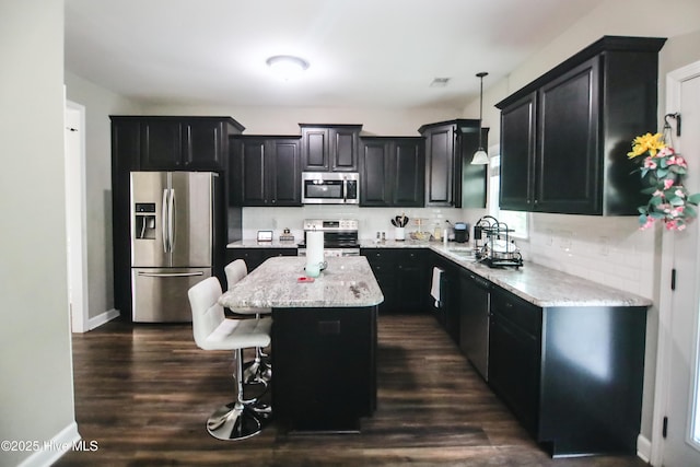 103 Stafford Dr, Pikeville, NC 27863 - kitchen featuring stainless steel appliances, dark cabinetry, tasteful backsplash, a center island, and a kitchen breakfast bar