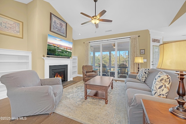 4277 Kingston Ct, Southport, NC 28461 - living room featuring a ceiling fan, lofted ceiling, a warm lit fireplace, and wood finished floors