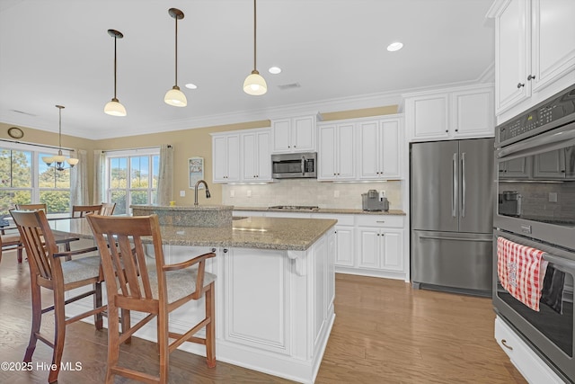 4277 Kingston Ct, Southport, NC 28461 - kitchen featuring appliances with stainless steel finishes, ornamental molding, tasteful backsplash, white cabinets, and light wood-style flooring